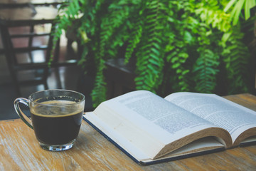 Cup of coffee and a book on a wooden table