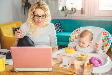 Mother with baby working on laptop at home office