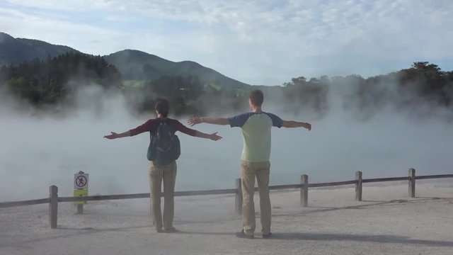 Boy and girl standing near boiling champagne pool in Wai-O-Tapu park, New Zealand