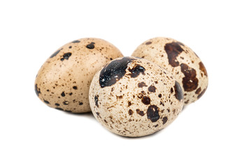 Three raw quail eggs on a white background