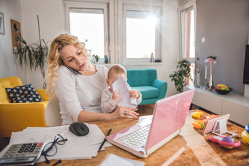 Mother talking on smart phone at home office