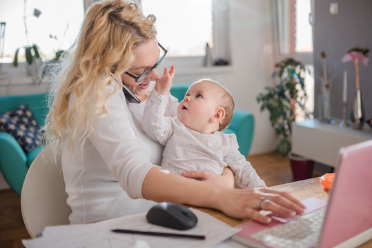 Mother talking on smart phone at home office
