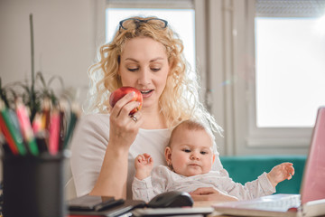 Mother eating apple at home office