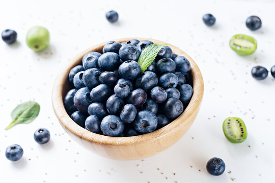 Fresh blueberries in wooden bowl over white background