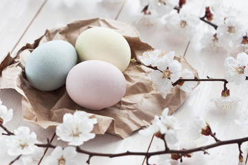 Colored eggs with flowers on a white wooden background. The concept of the holiday of Easter.