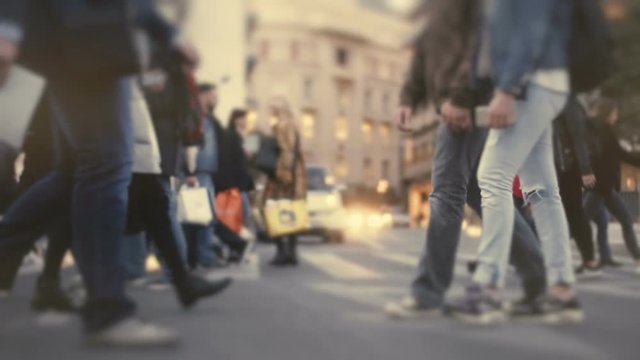 Group of pedestrians cross busy big city street at sunset.100 fps slow motion of a crowd of anonymous backlit pedestrians crossing a busy intersection in the afternoon