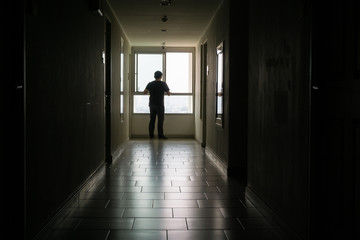 Silhouette of man standing alone,Sad and Serious Man stand alone of close room hospital., Dramatic moment.