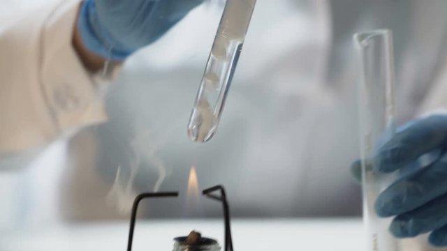 Chemist pouring boiling fuming liquid into test tube, conducting experiment