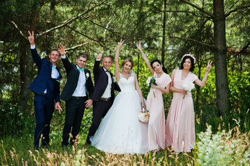 Fashionable wedding couple with bridesmaids on pink dresses and best mans with turqoise bow ties at...
