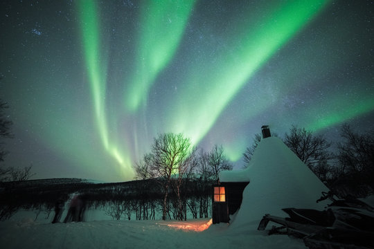 Illuminated snow covered cabin under the northern lights