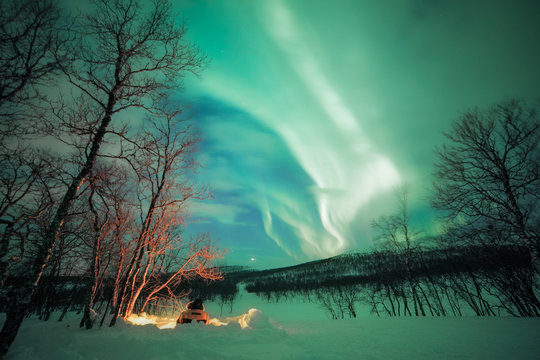 Man sits at camp fire under the northern lights