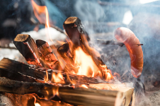 Close up of sausage cooking on log fire