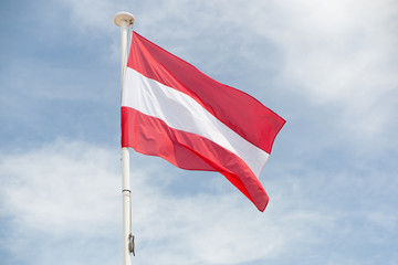 Austrian flag floats in the wind hanging from a mast