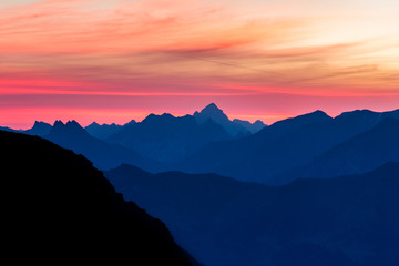 Spectacular blue mountain ranges silhouettes and pink violet clouds
