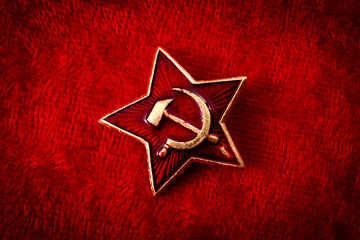 Old Soviet badge with the red star, a sickle and a hammer reminiscent of the cold war era worn by...