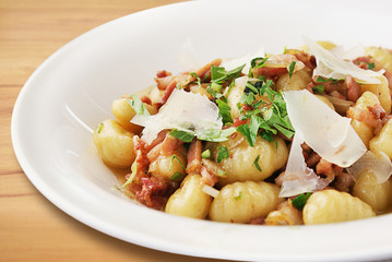 Gnocchi with bacon and parmesan on white plate.