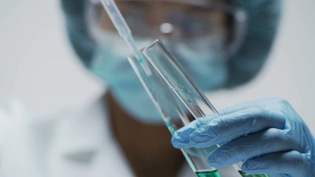 Female scientist observing reaction in test tubes after mixing two substances