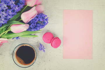 Obraz na płótnie Canvas Pink tulips and blue hyacinths flowers with cup of coffee on white wooden table with copy space on pink paper card, retro toned
