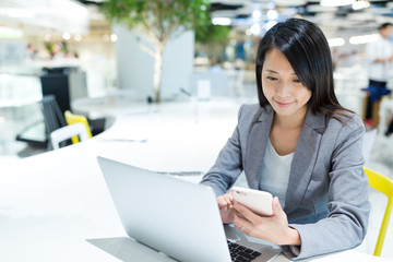 Fototapeta premium Woman using laptop and cellphone together