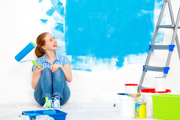 Repair in apartment. Happy woman paints wall