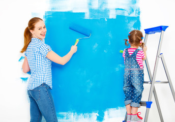Repair in apartment. Happy family mother and child daughter paints wall .