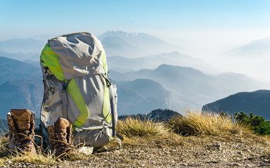 Hiking equipment. Backpack and boots on top of mountain. - 141901497