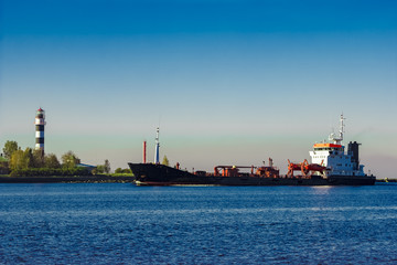 Black cargo oil tanker entering the port of Riga at sunny day