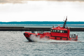 Fototapeta premium Red pilot ship sailing to Baltic sea past the breakwater dam