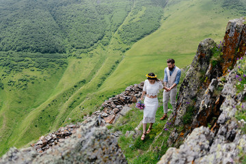 Naklejka premium young couple in love, enjoying their trip in the mountains. Side view with large beautiful mountains in the foreground