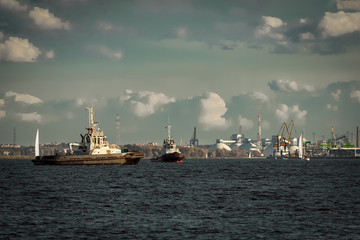 Two tug ships are accepting cargo vessel at Daugava river