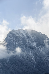 Fototapeta na wymiar Carpathians Mountains, Bucegi range with Cross in top of Caraiman Peak, pine forest with fog, winter time with snow