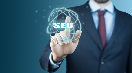 Business man holding SEO text on screen