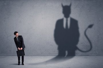 Business man looking at his own devil demon shadow concept