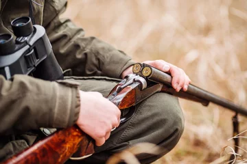 Zelfklevend Fotobehang jager die geweer in een de winterbos laadt. Bushcraft, jacht en mensenconcept © kaninstudio
