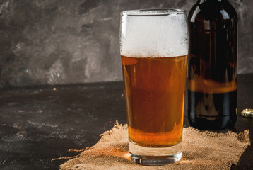 One open bottle of beer, a glass of beer, a foam. On a concrete background, copy space