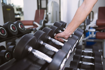 Plakat Hand of man taking a dumbbell out of set of black weights