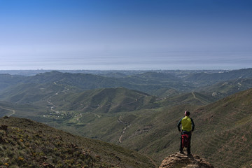 Obraz premium Hombre en la cima de la montaña que mira el paisaje montañoso