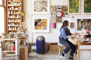 Side view of artist working at table in workshop