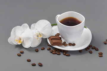 Orchid and white cup of coffee on a gray background