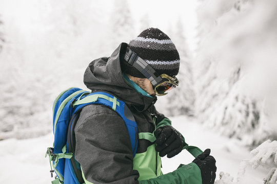 Side view of man fastening belt while standing on snow covered field