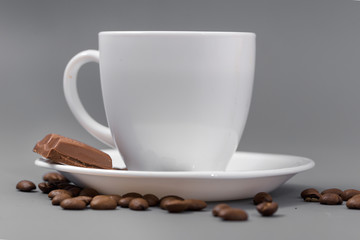 White cup of coffee with candy on a gray background