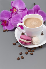 White cup of coffee with candy on a gray background