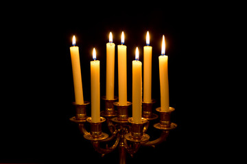 Chandelier with burning candles on black background