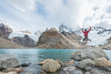 Man jumping for joy at Laguna de Los Tres at the base of Mount Fitz Roy in El Chalten, Argentina in Patagonia