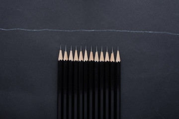A set of black pencils on a black background are beautifully arranged.