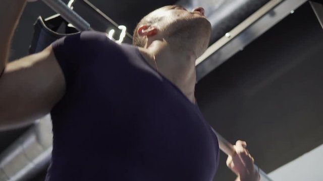 A young man is practicing at the gym. He crouches with a barbell. 4K