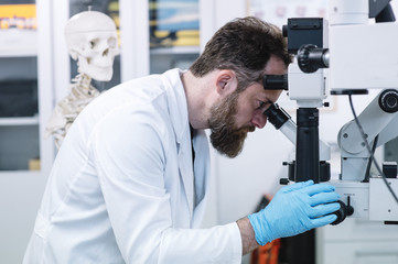 Naklejka na ściany i meble Scientist in laboratory looking through microscope