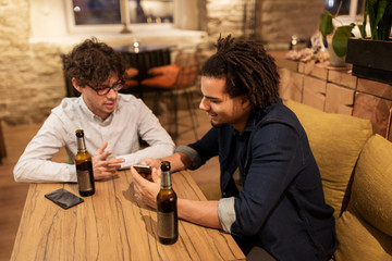 men with smartphones drinking beer at bar or pub