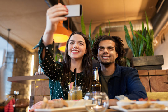 happy couple taking selfie at cafe or bar