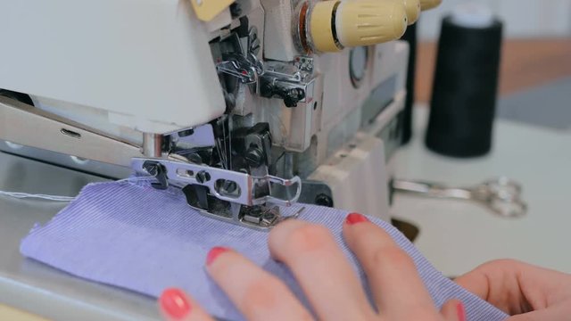 Professional tailor, seamstress using overlocking sewing machine. Fashion and tailoring concept
